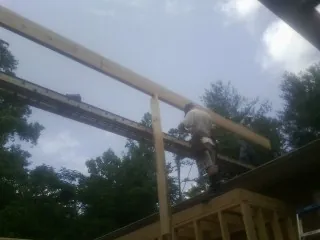 Carpenter setting a ridge beam over a new addition frame — Ice Dam Removal by Roofing Brothers in Wessington
