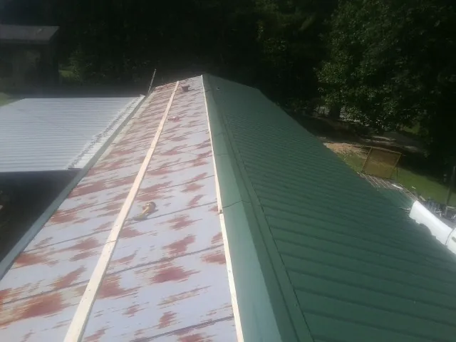 Old rusted panels beside newly installed green metal roofing — Wind Damage Roof Repair by Roofing Brothers in Wessington