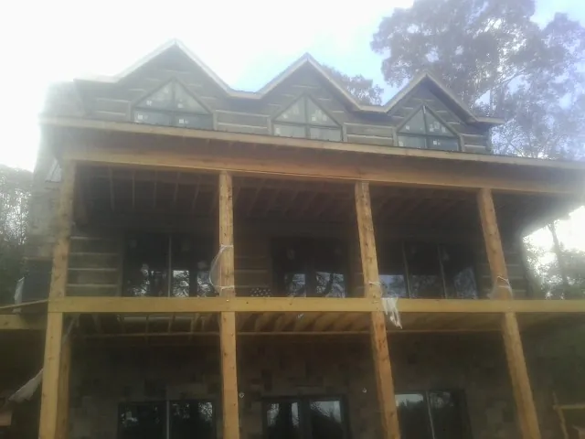 Dormers and porch framing on a large log home under construction — Roof Coating work by our crew in Wessington