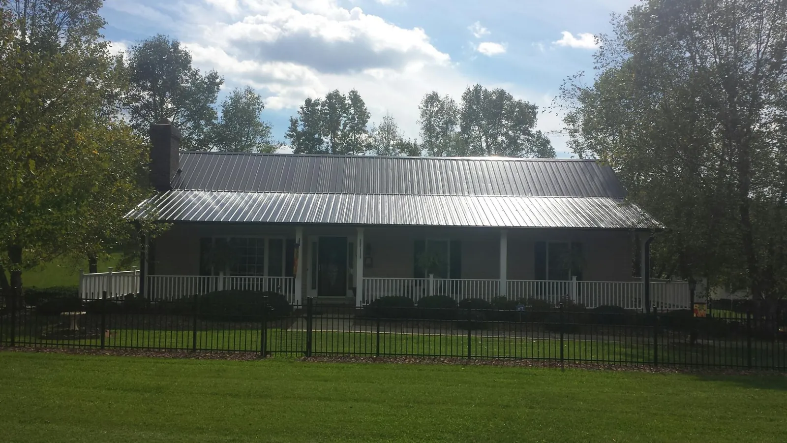 Gray metal roof on a brick ranch with a full width front porch — Gutter Guard Installation work by our crew in Wessington